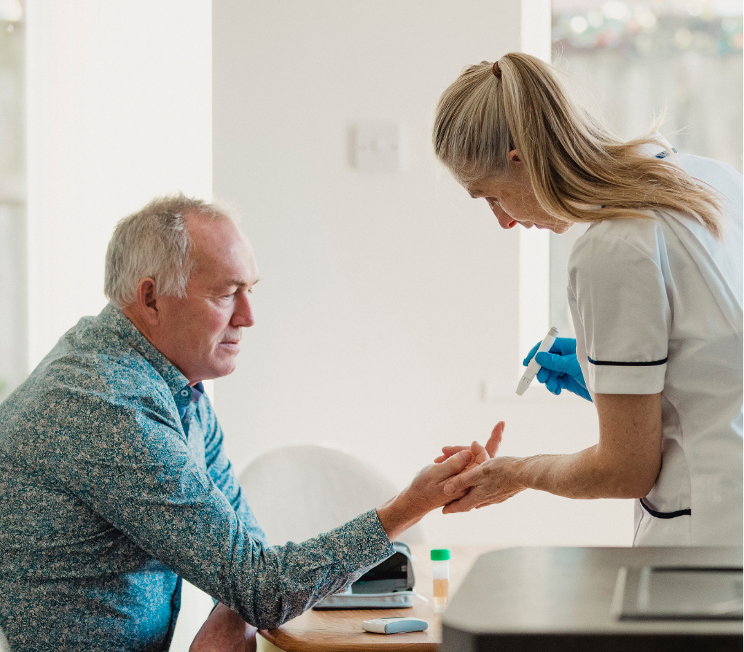 diabetes-management-3 Elderly man receives a glucose test from a nurse in a white uniform and blue gloves at home.
