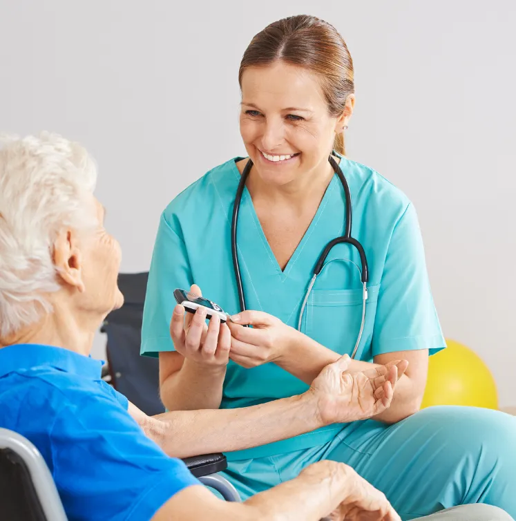 diabates-2 Smiling nurse in scrubs checks an elderly woman's blood sugar with a glucometer.