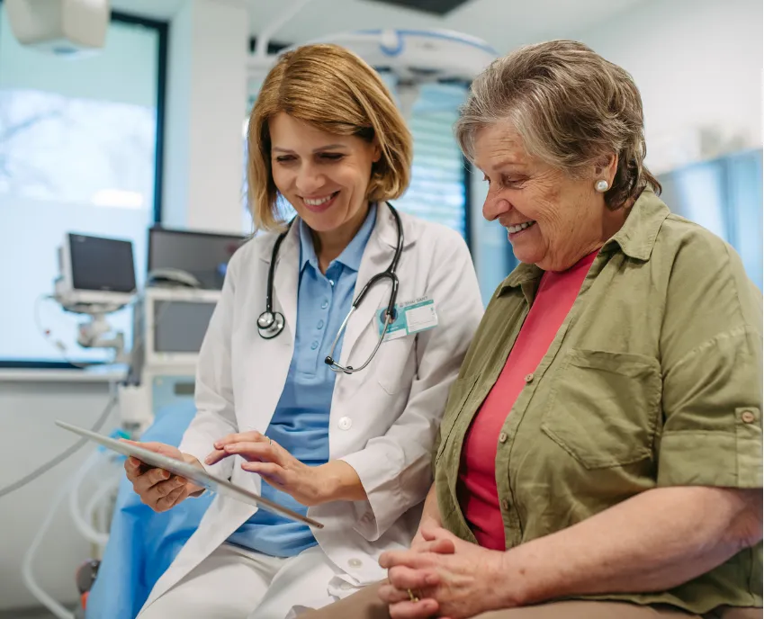 screening-1 Smiling doctor shows an older woman information on a tablet in a medical office.
